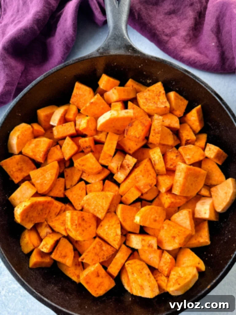 Sweet potato slices cooking in a cast iron skillet over medium-high heat, showing the initial browning stage.