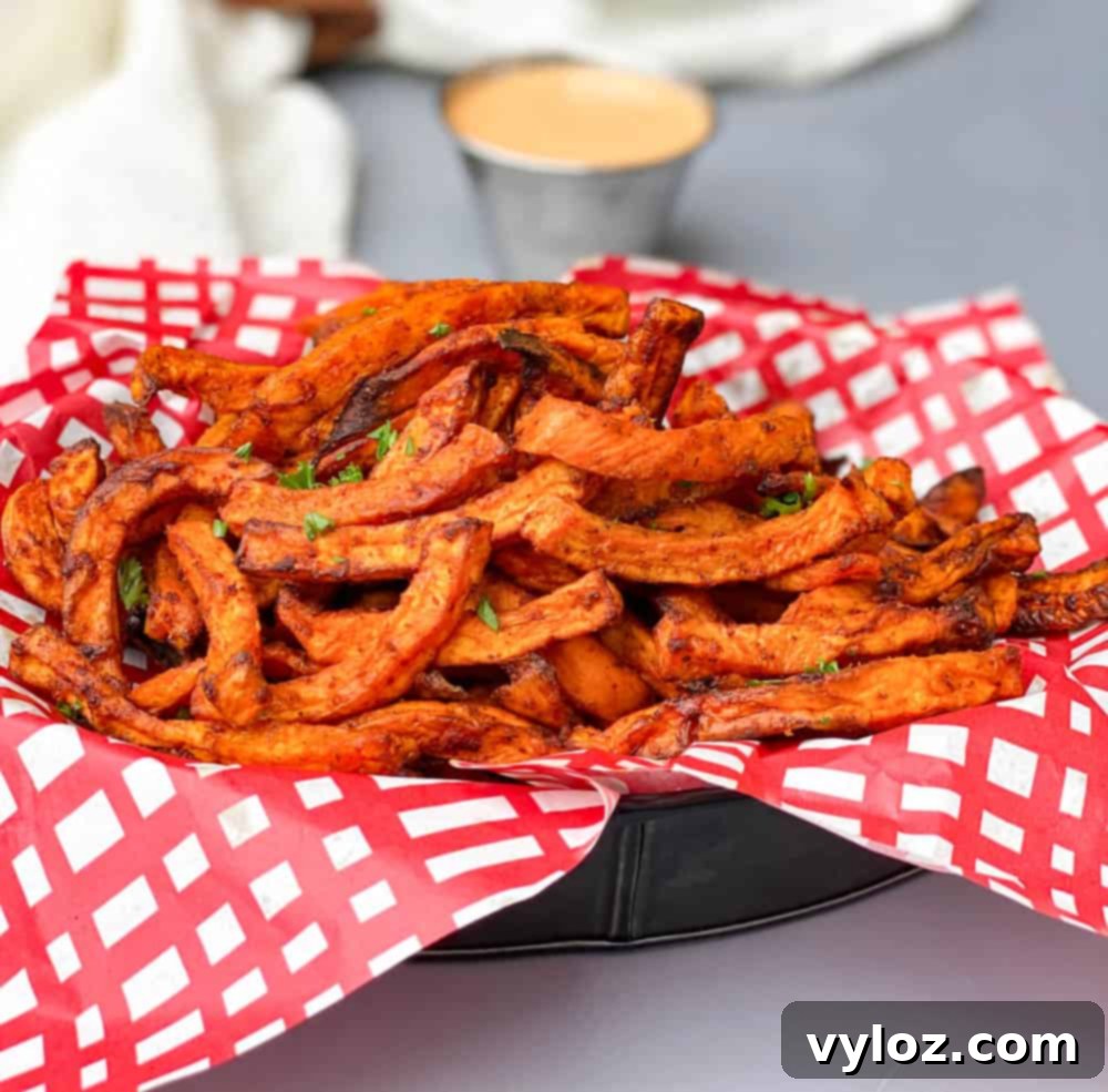 air fryer sweet potato fries in a basket with a red and white napkin and chipotle mayo