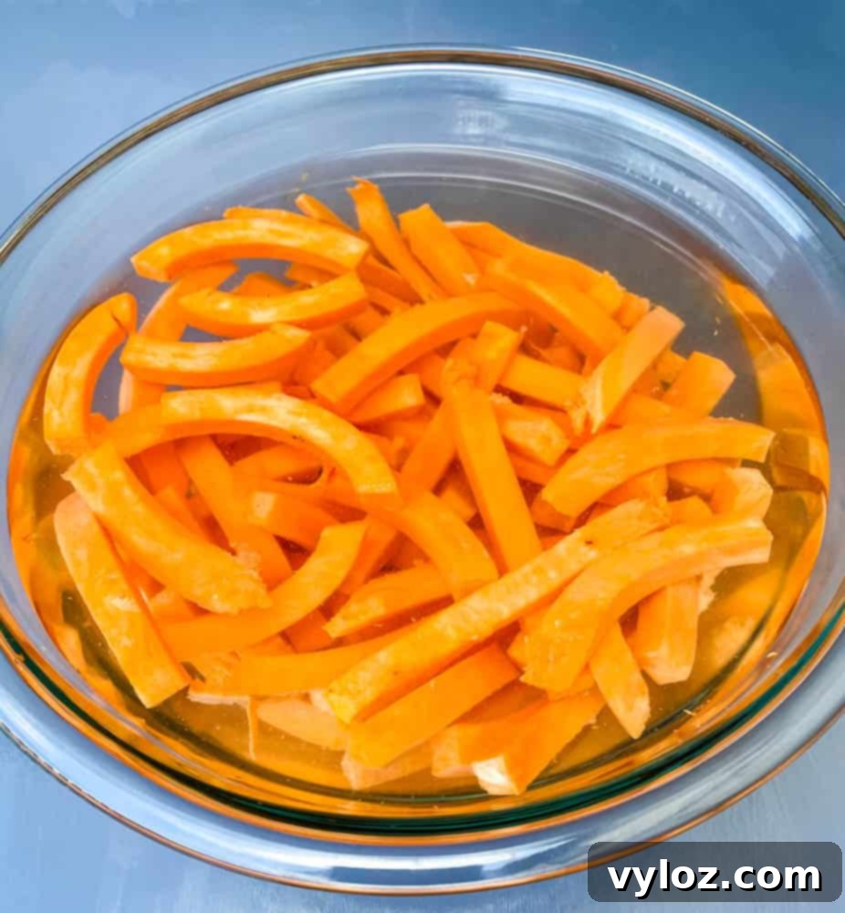 raw sweet potatoes sliced and in a glass bowl filled with water