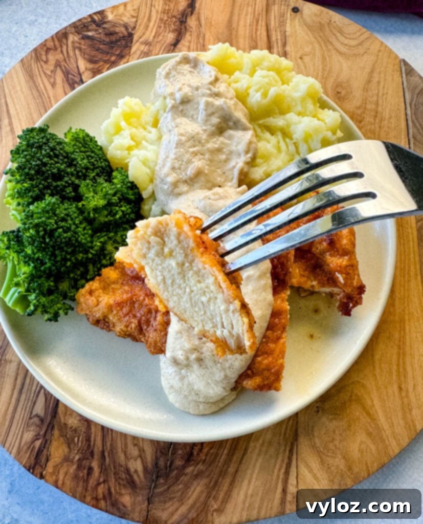 Close-up of a fork lifting a bite-sized piece of chicken fried chicken, glistening with homemade country gravy.