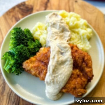chicken fried chicken with gravy, mashed potatoes, and broccoli on a plate