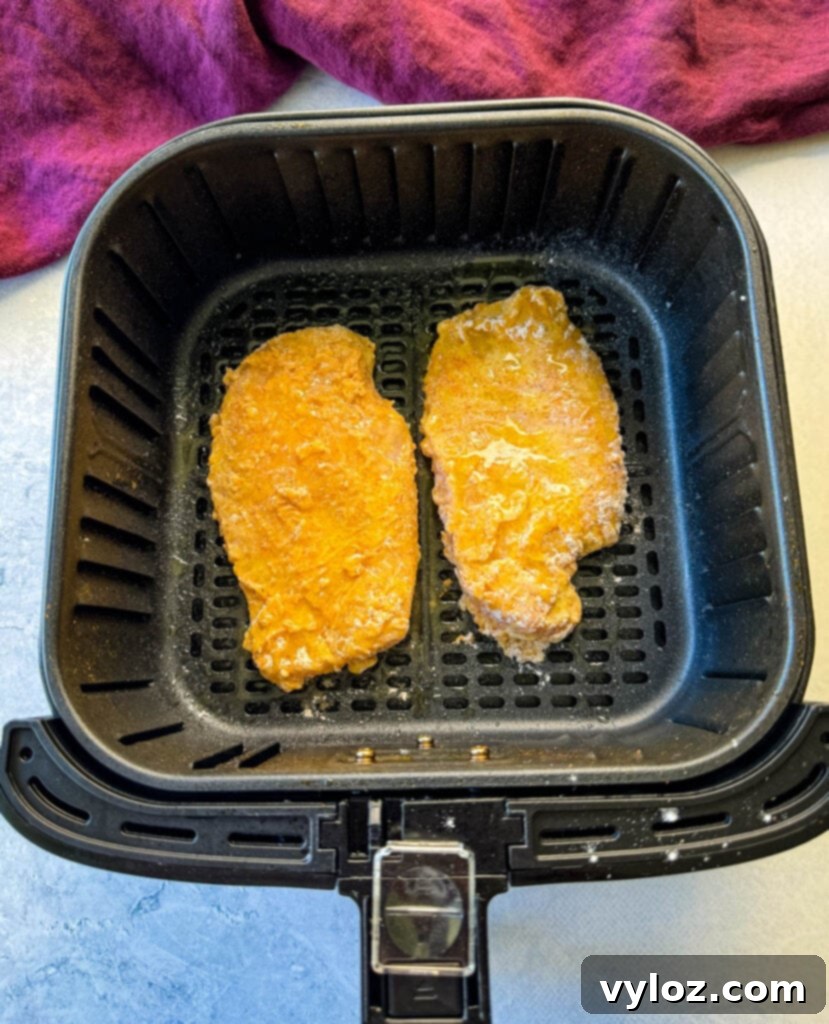 Uncooked, breaded chicken fried chicken pieces neatly arranged in an air fryer basket, ready to cook.