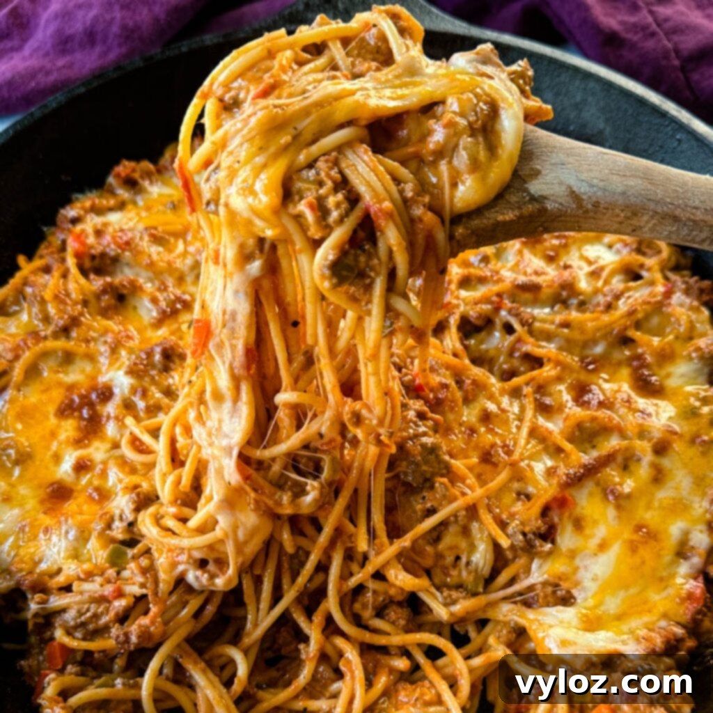 million dollar spaghetti in a cast iron skillet with a wooden spoon