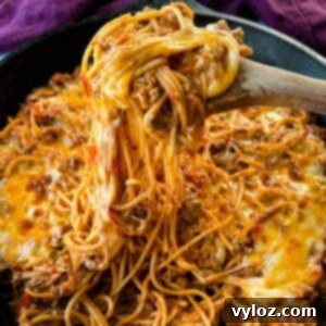 million dollar spaghetti in a cast iron skillet with a wooden spoon
