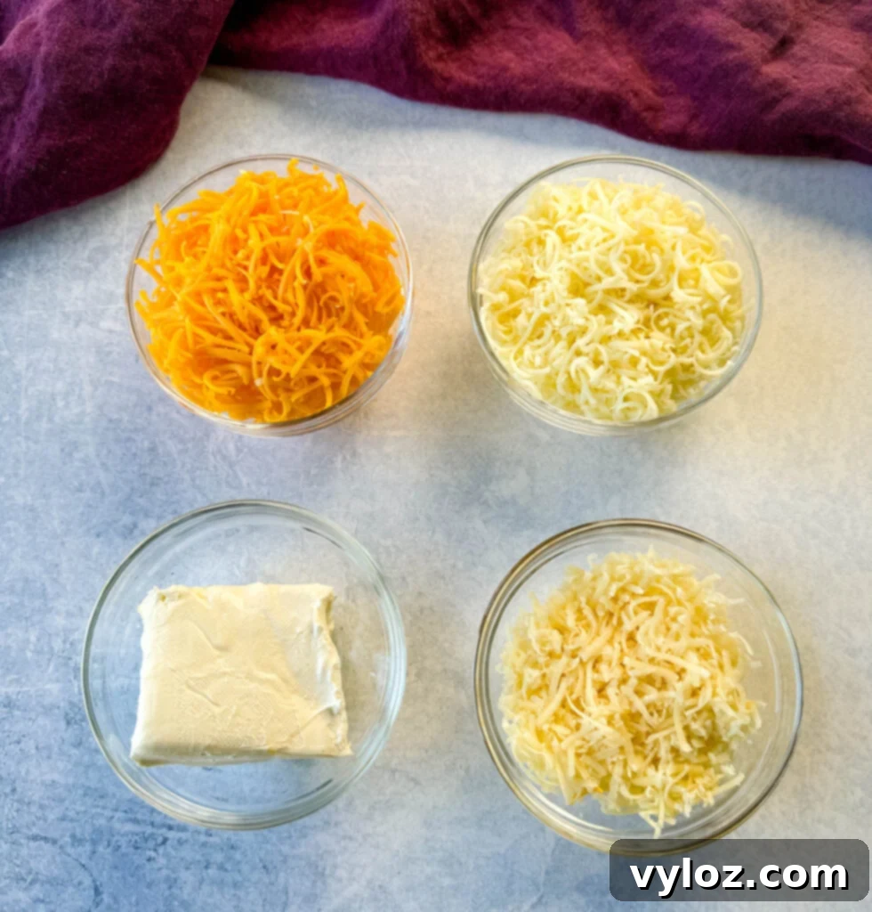 grated cheddar cheese, grated, mozzarella cheese, grated Parmesan cheese, and cream cheese in separate glass bowls