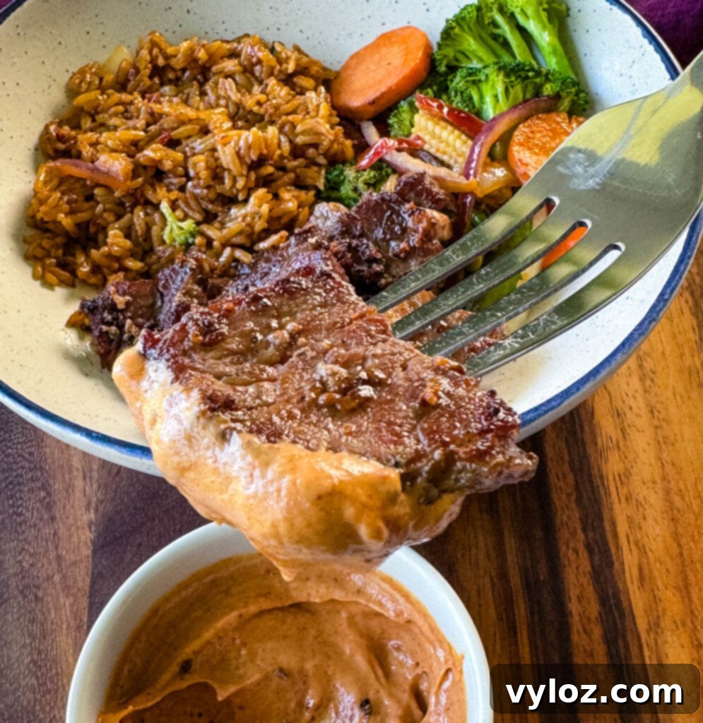 a fork dipped with steak and sauce over a hibachi bowl