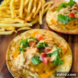 Cheesy Taco Burgers 14 cheeseburger tacos with tomatoes, lettuce, and burger sauce on a plate with fries