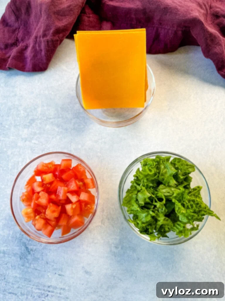 Cheesy Taco Burgers 8 diced tomatoes, chopped lettuce, and slices of cheese in separate glass bowls