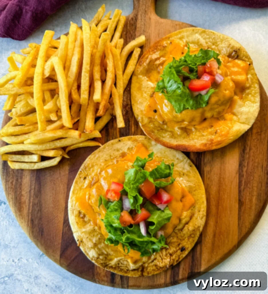 Cheesy Taco Burgers 10 cheeseburger tacos with tomatoes, lettuce, and burger sauce on a plate with fries