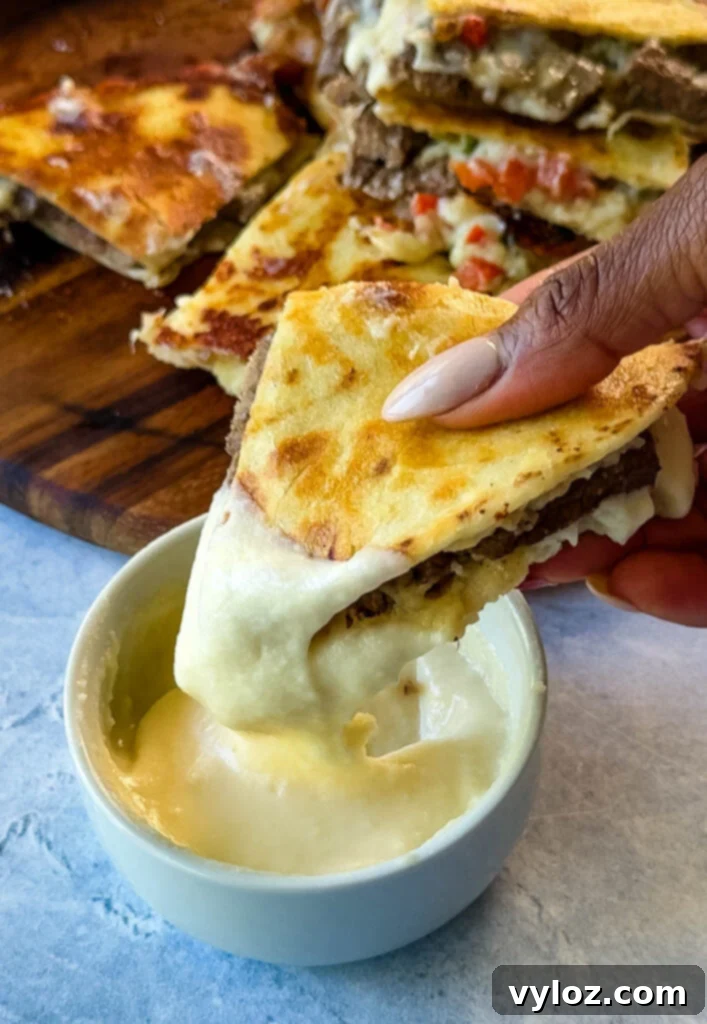 person holding Philly cheesesteak quesadilla with homemade Cheez Whiz