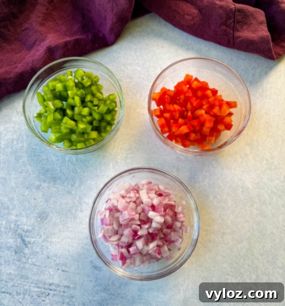 green and red bell peppers and red onions in separate glass bowls