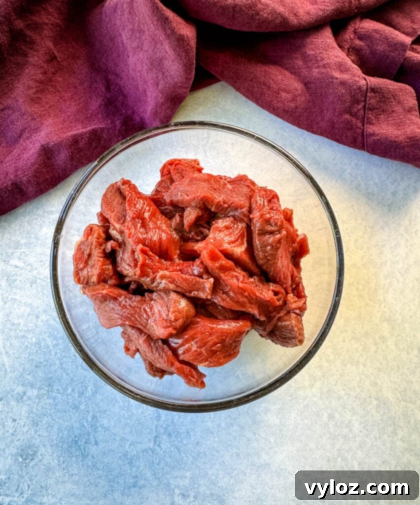 raw steak sliced into strips in a glass bowl
