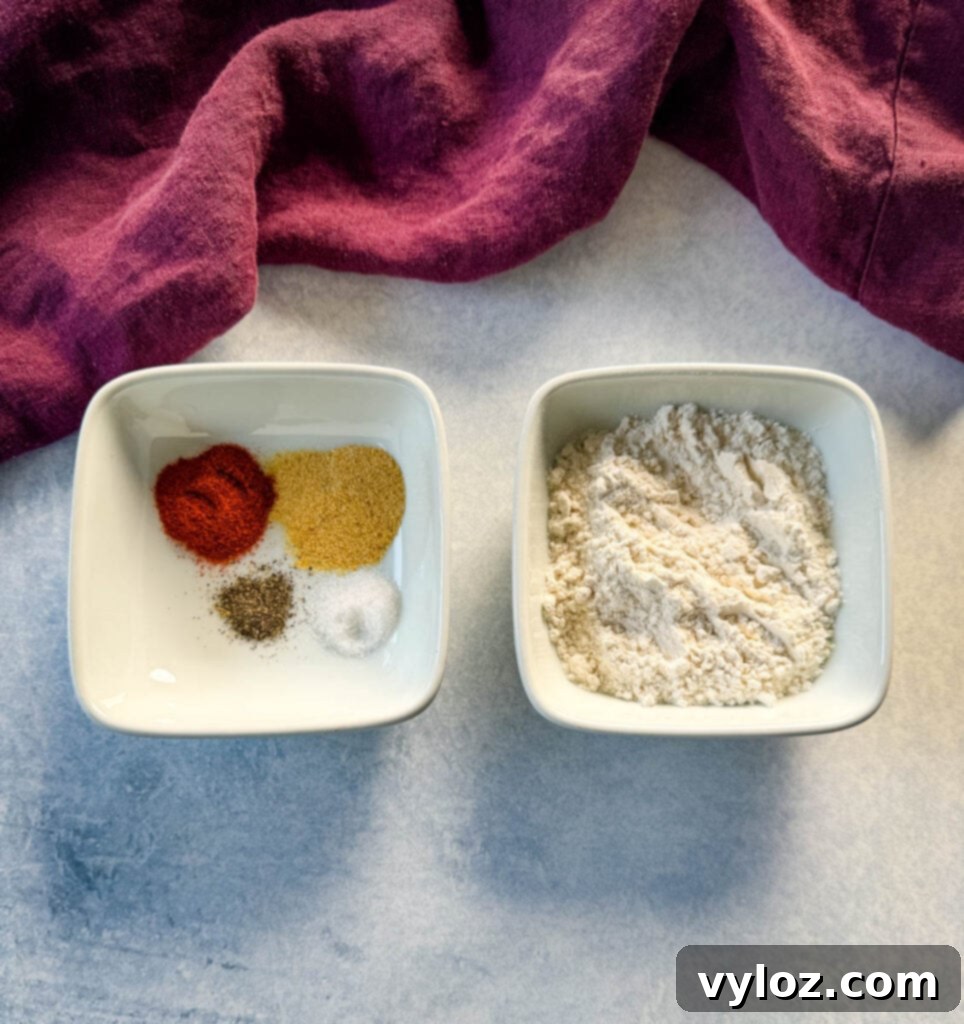 Seasoning ingredients for chicken: all-purpose flour, smoked paprika, garlic powder, salt, and pepper, presented in two white bowls.