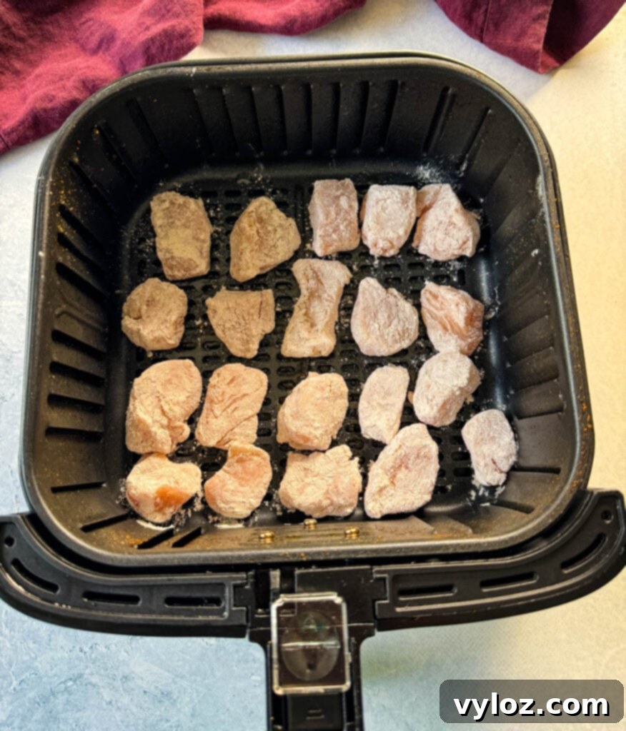 Raw seasoned chicken breast pieces arranged in an air fryer basket, ready for cooking.