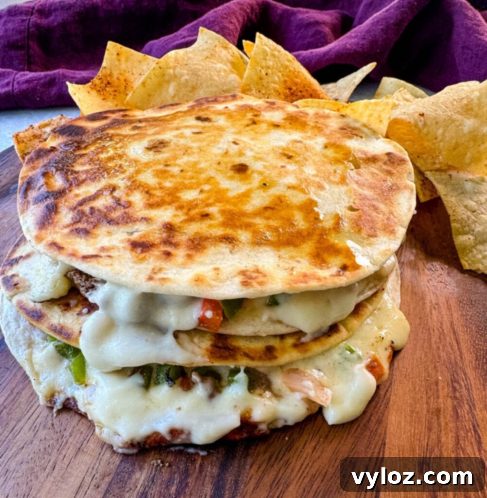 A delicious Philadelphia cheesesteak sandwich on a flat surface, served alongside potato chips and ready for homemade Cheez Whiz