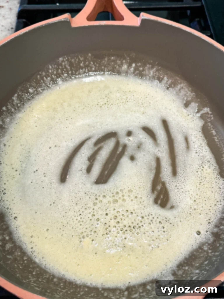Flour being whisked into melted butter in a skillet to form a roux