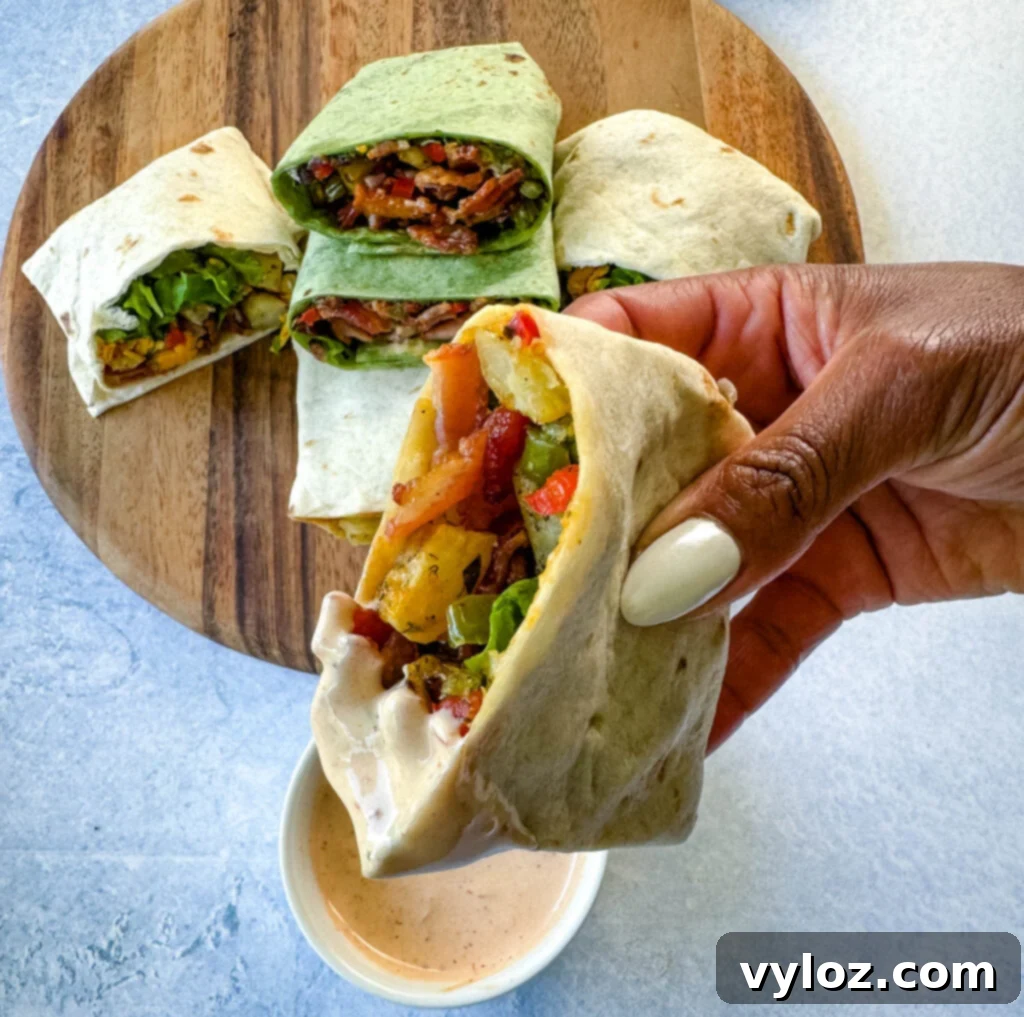 person holding breakfast burrito with bacon, potatoes, bell peppers and cheese