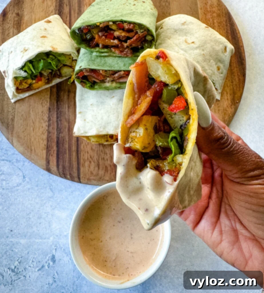 person holding breakfast burrito with bacon, potatoes, bell peppers and cheese