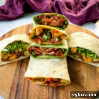 breakfast burritos with bacon, potatoes, bell peppers and cheese on a flat surface