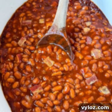 Smoky Slow Cooker Bacon Baked Beans 12 baked beans in a slow cooker Crockpot with a wooden spoon