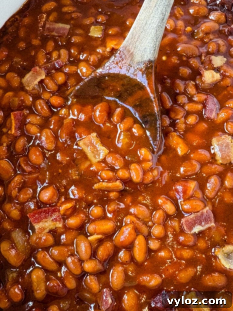 Smoky Slow Cooker Bacon Baked Beans 9 baked beans in a slow cooker Crockpot with a wooden spoon