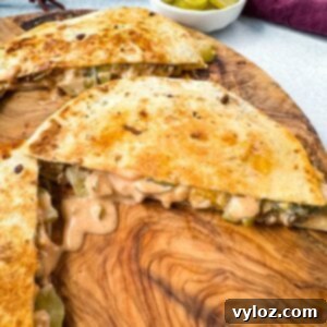 cheeseburger quesadilla with pickles and burger sauce on a wooden cutting board
