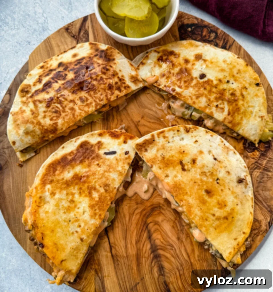 cheeseburger quesadilla with pickles and burger sauce on a wooden cutting board