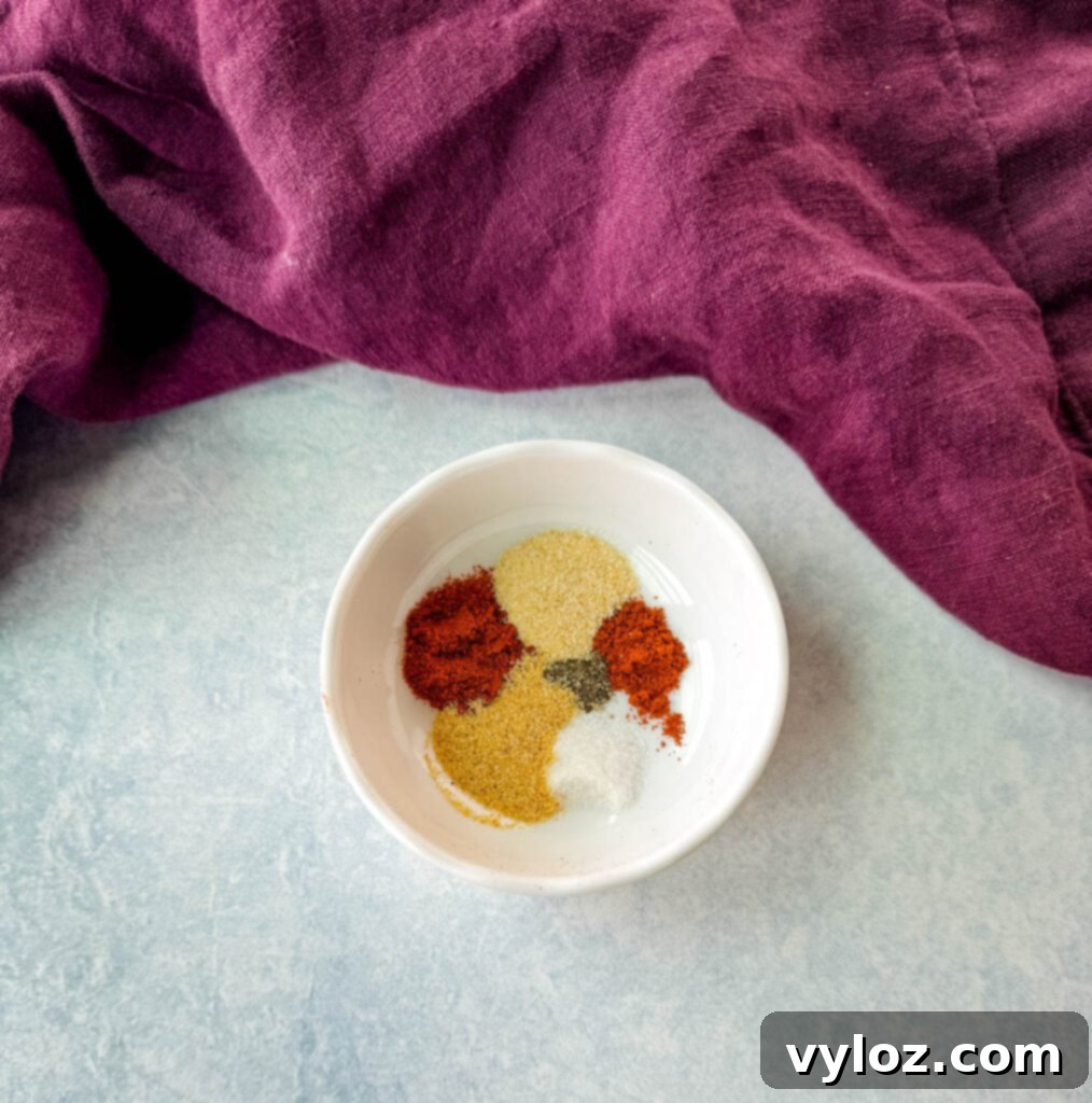 Smoked paprika, cayenne pepper, garlic powder, onion powder, salt, and pepper in a white bowl