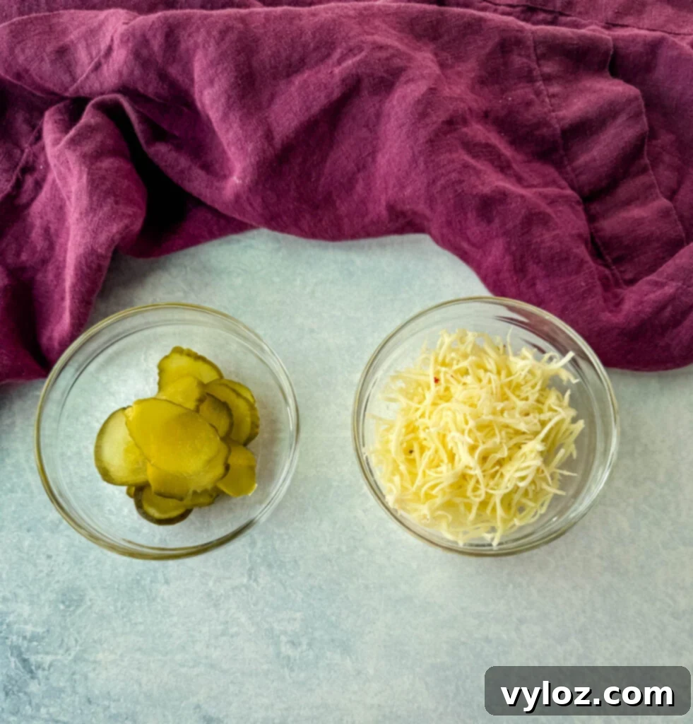 Pickles and grated pepper jack cheese in separate glass bowls
