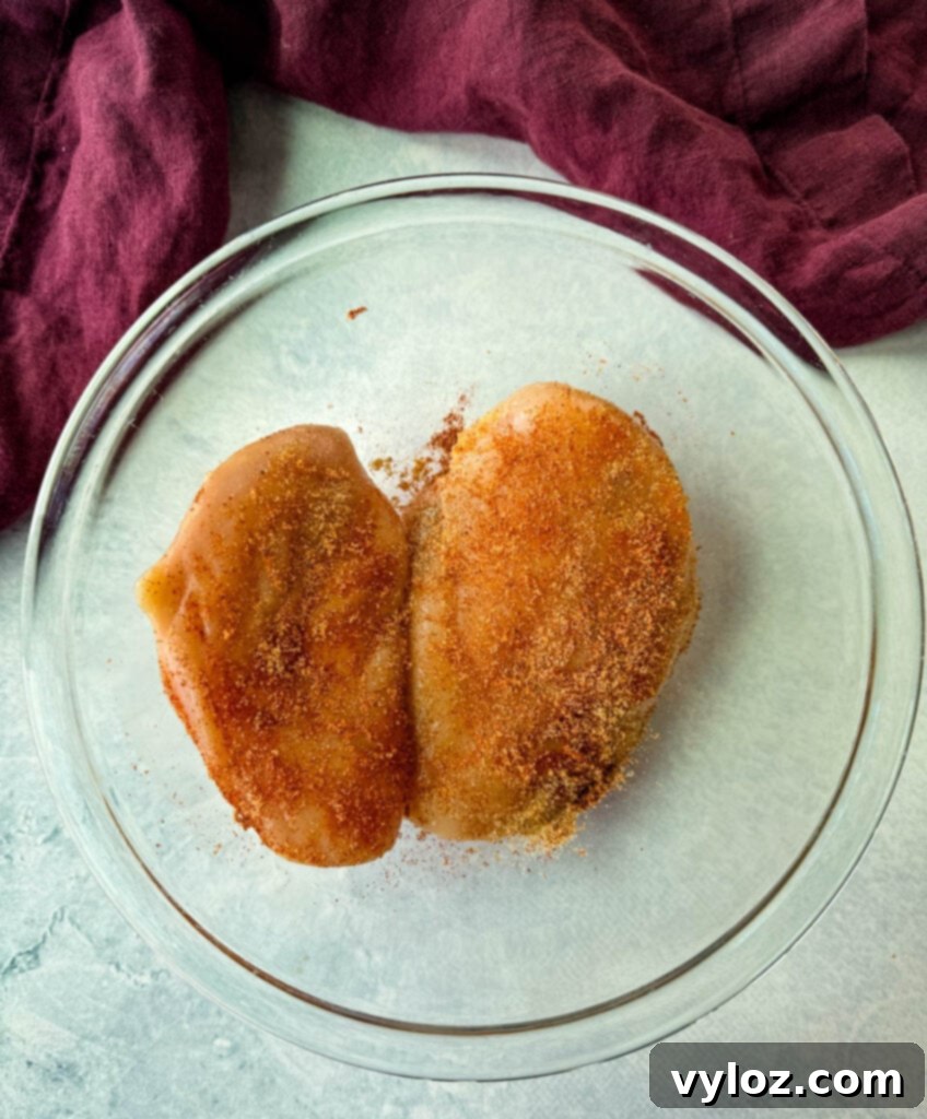Raw seasoned chicken breasts in a glass bowl
