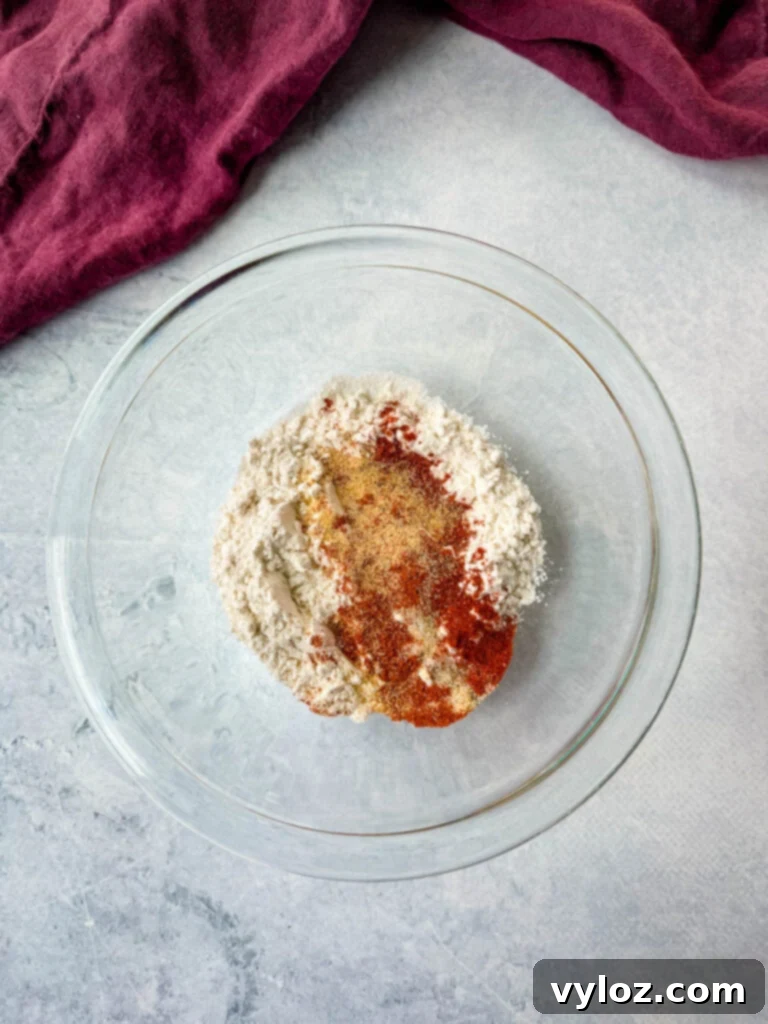 Sweet Heat Honey Chicken Bowls 6 All-purpose flour mixed with a blend of spices in a glass bowl, ready to coat the chicken.