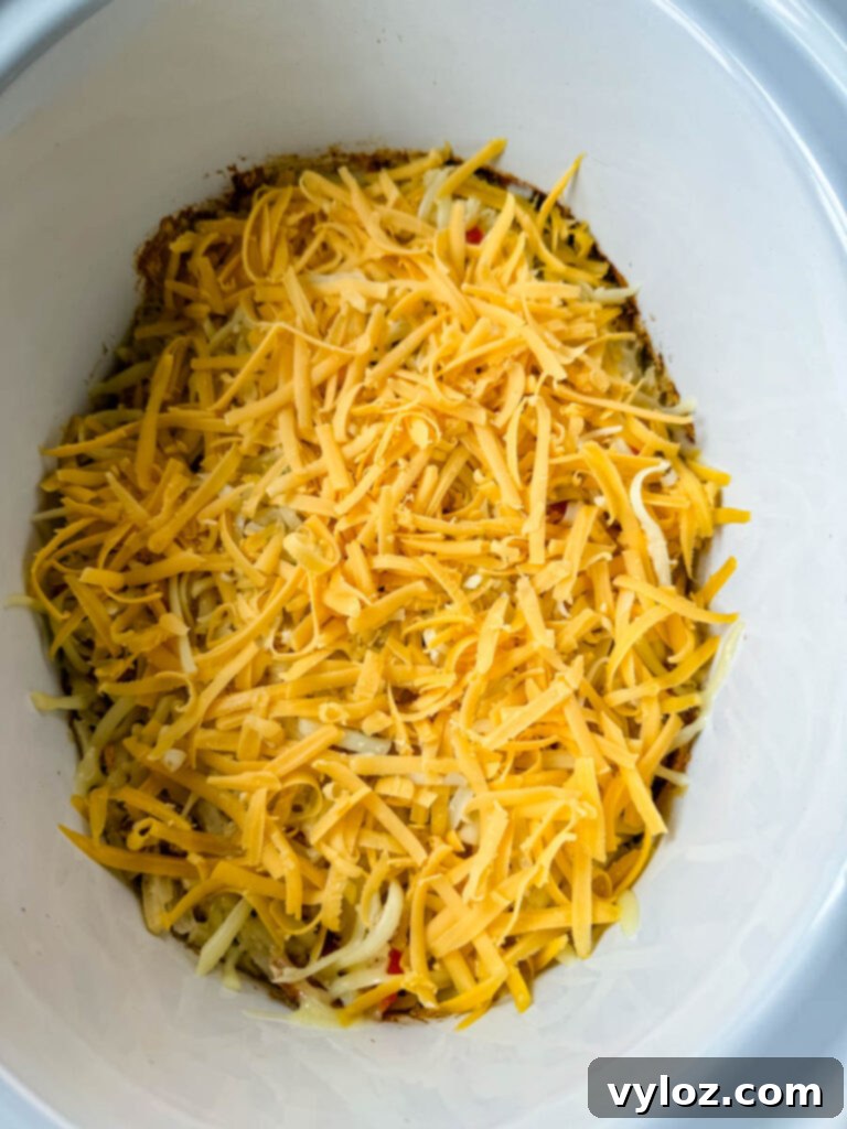 A close-up view of a creamy, cheesy hash brown casserole simmering in a Crockpot slow cooker, with melted cheese bubbling on top.
