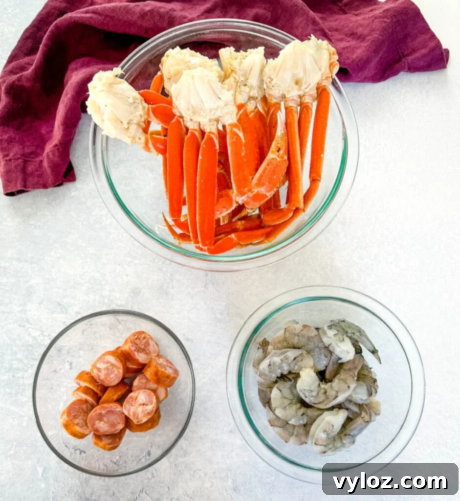 Garlic Butter Seafood Boil Bag 5 Snow crab clusters, andouille sausage, and raw shrimp in separate glass bowls, ready for the seafood boil.