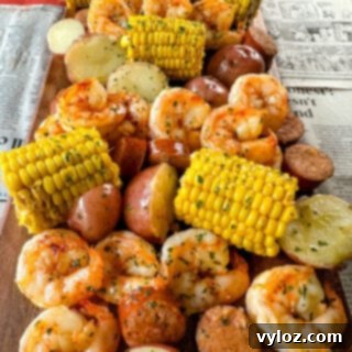 shrimp boil with andouille sausage, red potatoes, and corn on the cob on a flat surface with newspaper