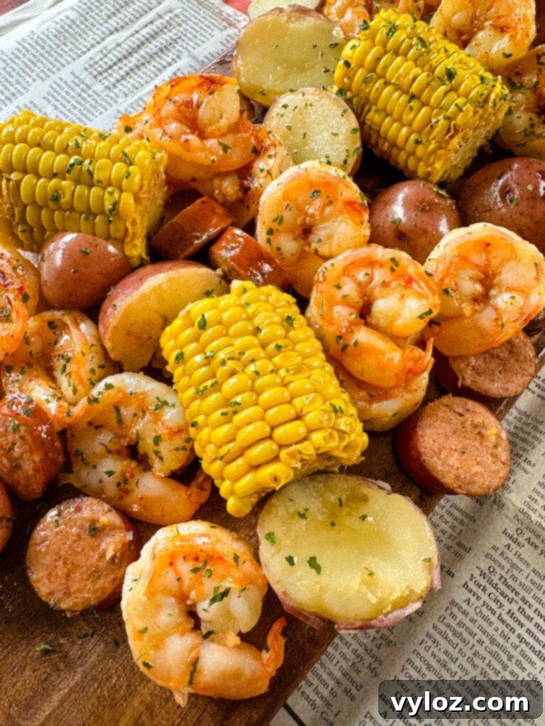 shrimp boil with andouille sausage, red potatoes, and corn on the cob on a flat surface with newspaper
