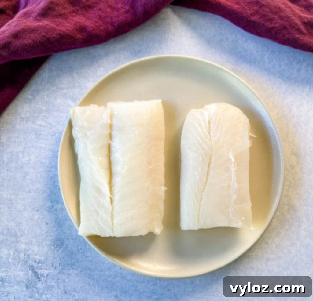 Golden Fried Fish Sandwich 4 raw cod fish fillets on a plate