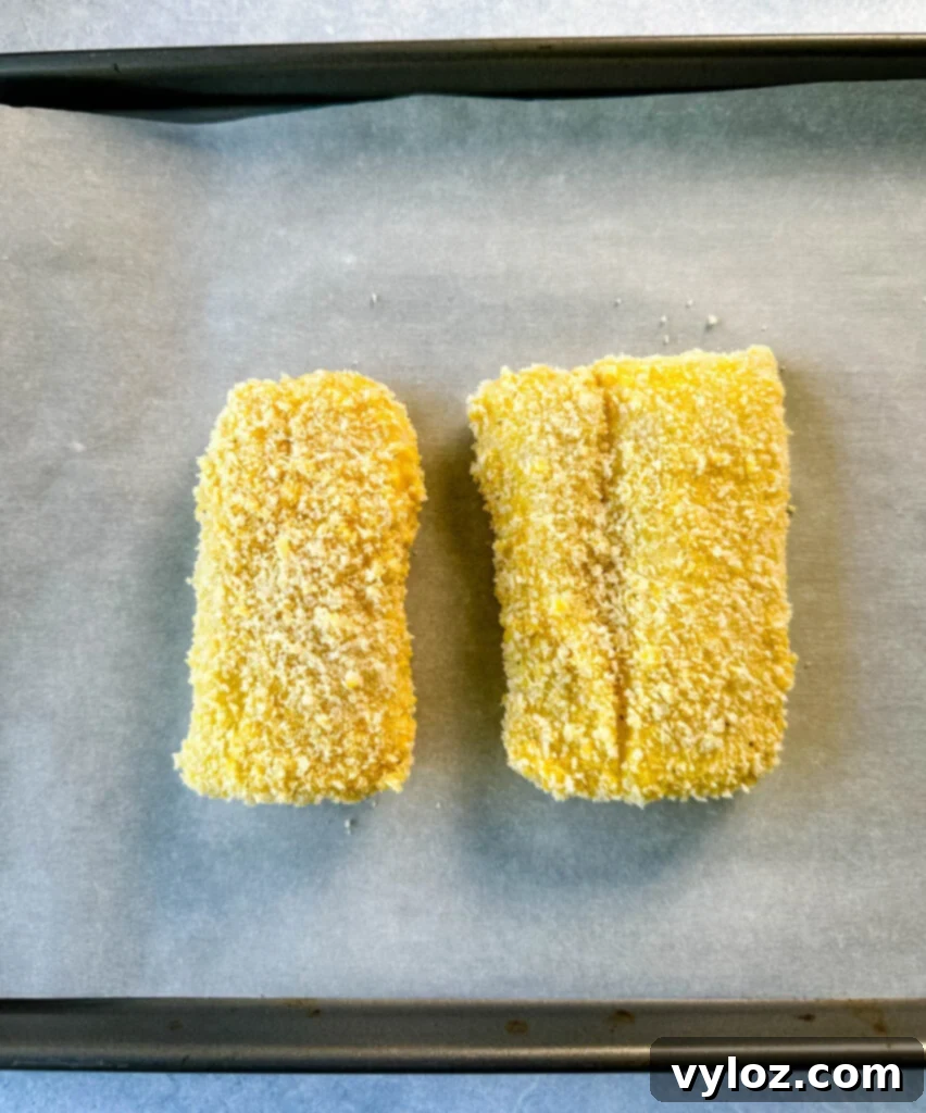 Golden Fried Fish Sandwich 8 breaded fish fillets on parchment paper and a sheet pan