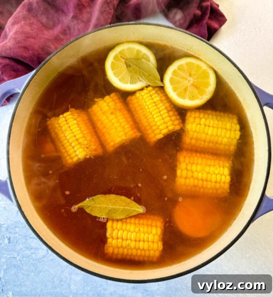 Cajun Crawfish Feast 5 Dutch oven filled with corn, lemon, bay leaf, potatoes, and sausage, simmering in a flavorful crawfish boil sauce