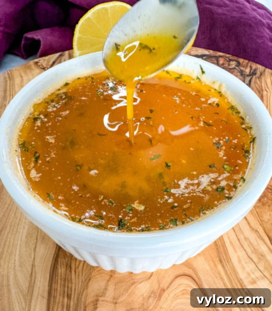 seafood boil garlic butter sauce in a white bowl with a spoon