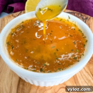 seafood boil garlic butter sauce in a white bowl with a spoon
