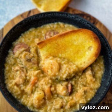 Cajun jambalaya soup in a black bowl with a piece of French bread