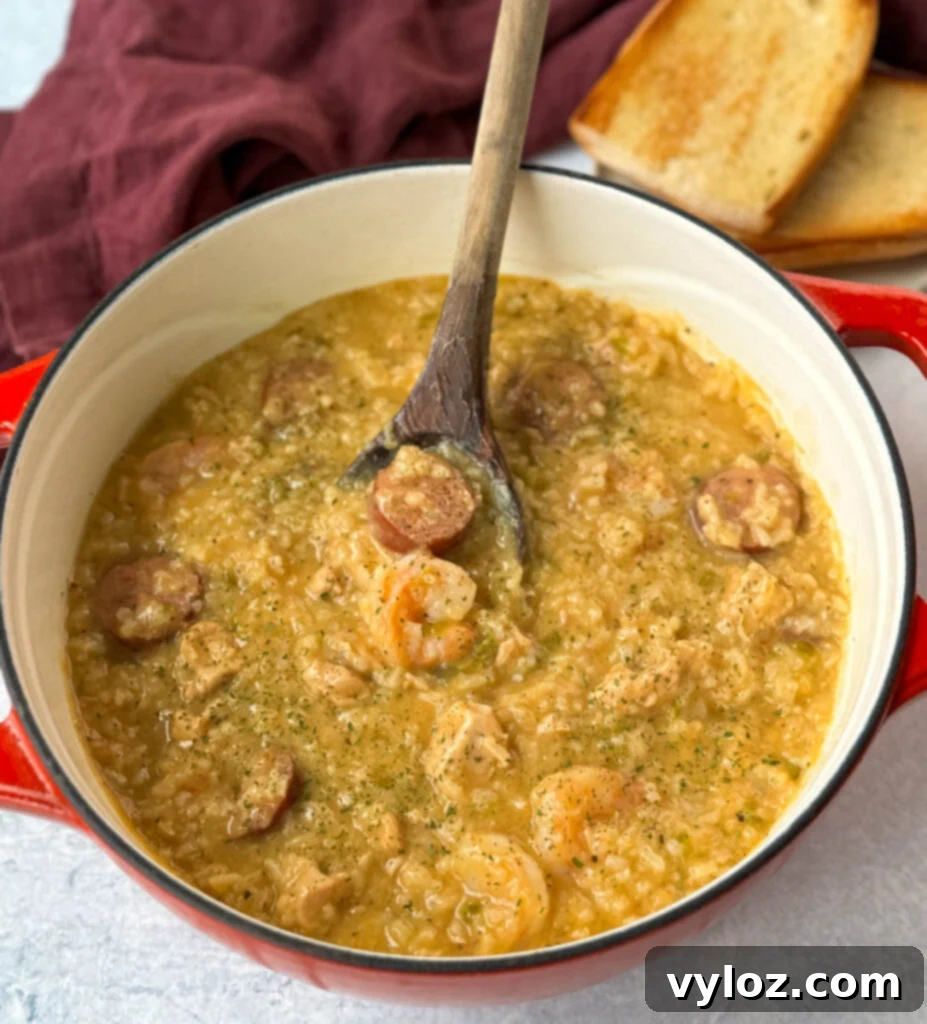 Cajun jambalaya soup in a Dutch oven with a wooden spoon