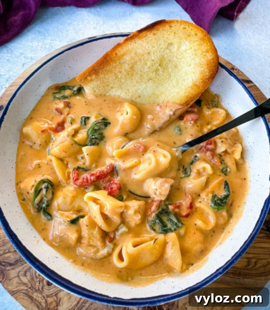 marry me Tuscan chicken soup in a white bowl with a piece of bread and a spoon