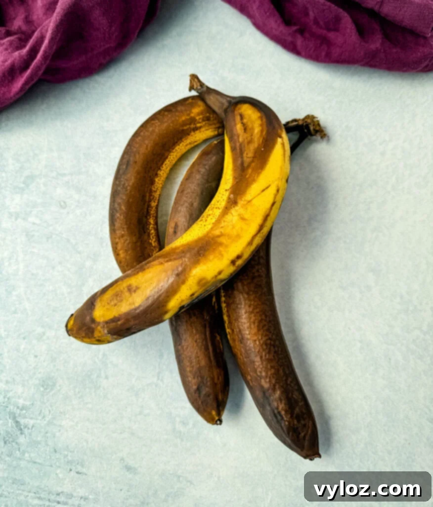 Several very ripe, brown-spotted bananas arranged on a flat surface, ideal for baking.