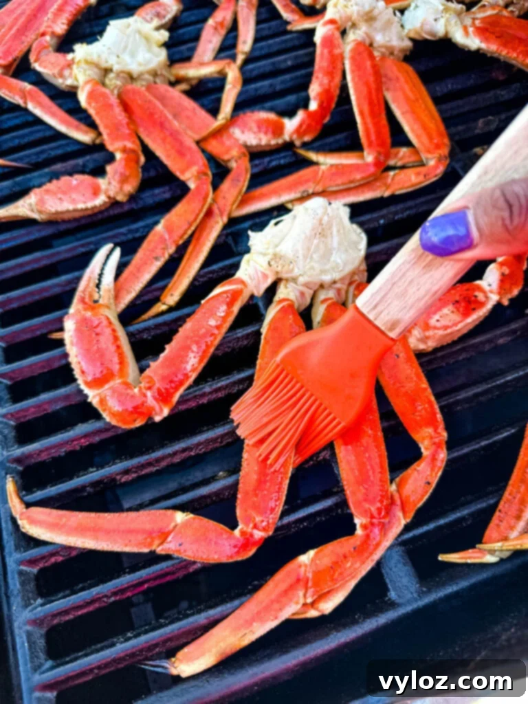 Grilled snow crab legs brushed with garlic butter sauce on a barbecue grill