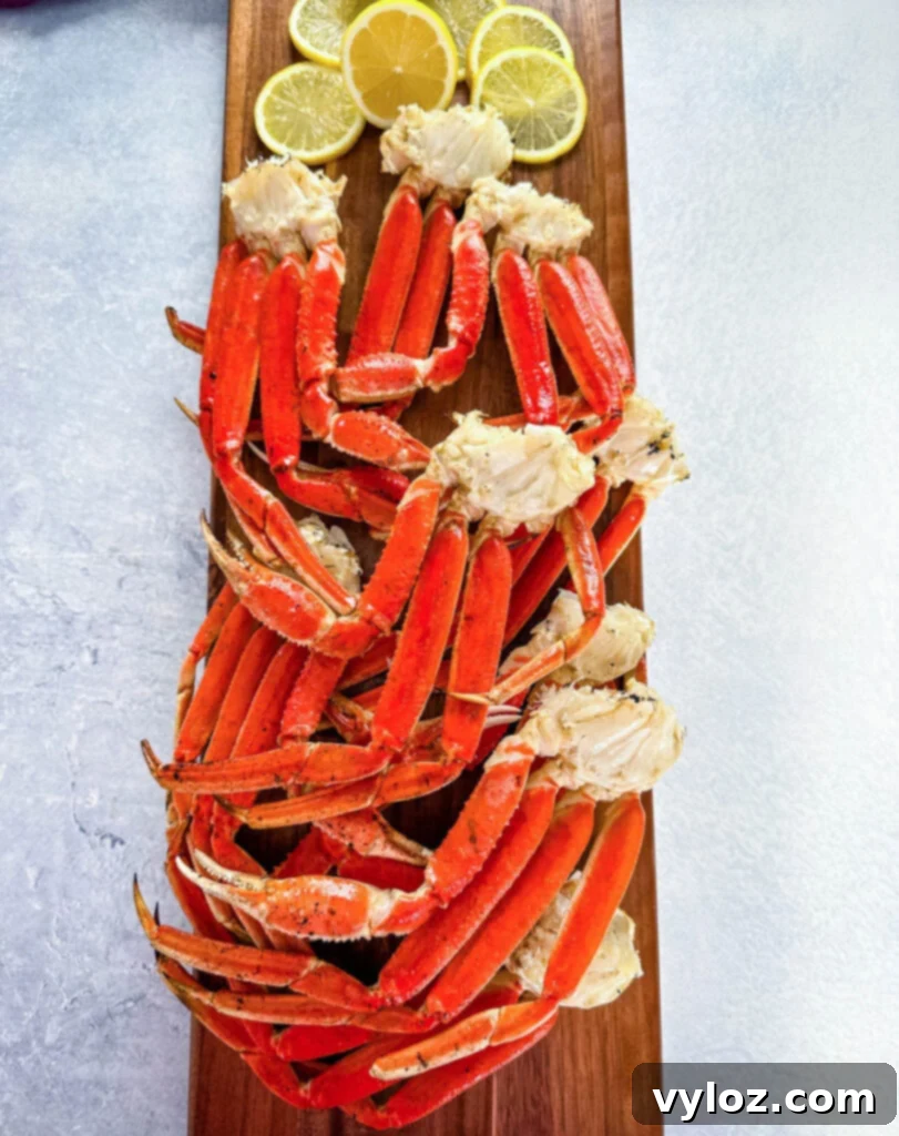 Grilled snow crab legs on a wooden serving board with fresh lemon wedges