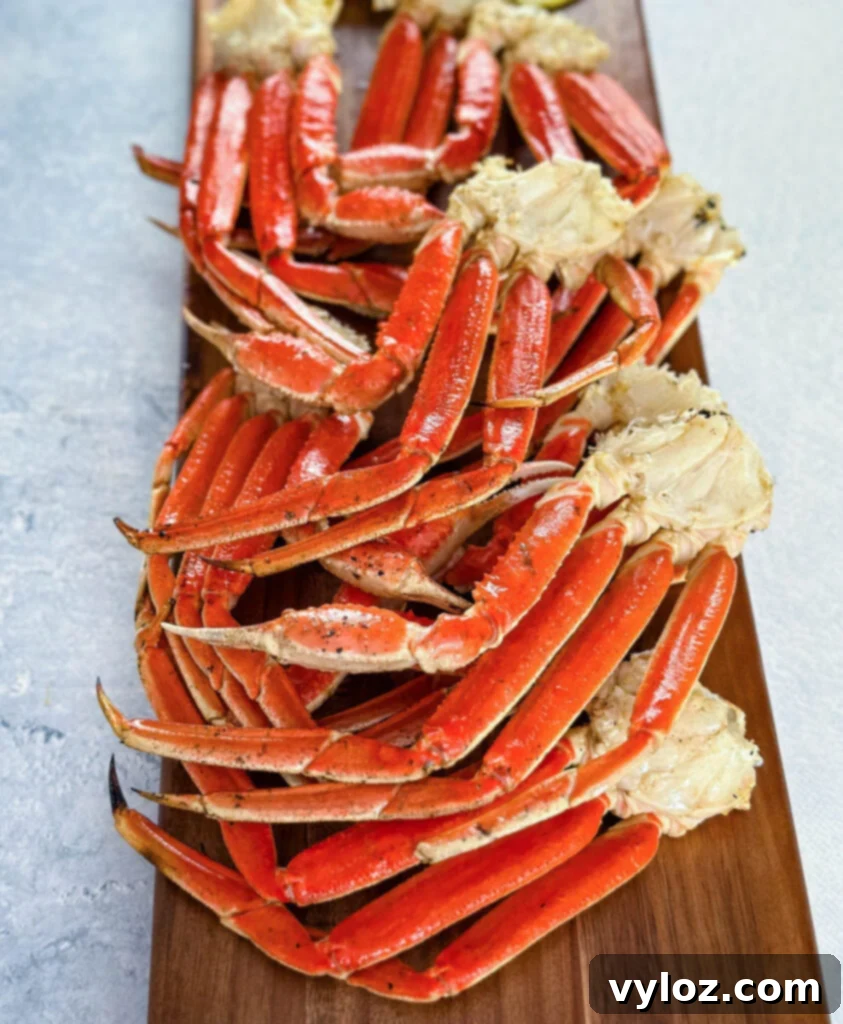 Freshly grilled snow crab legs arranged on a wooden board with lemon slices