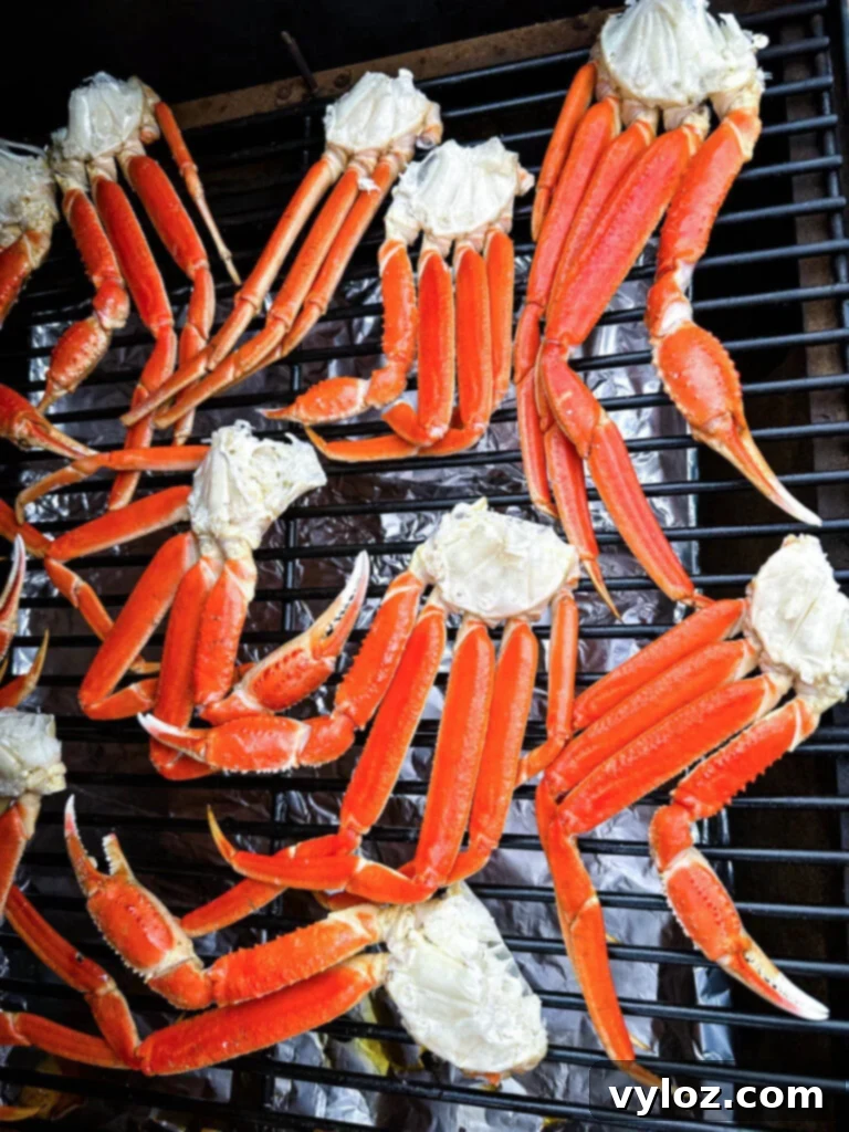 Crab legs carefully arranged on the grates of a Traeger pellet smoker, ready for smoking
