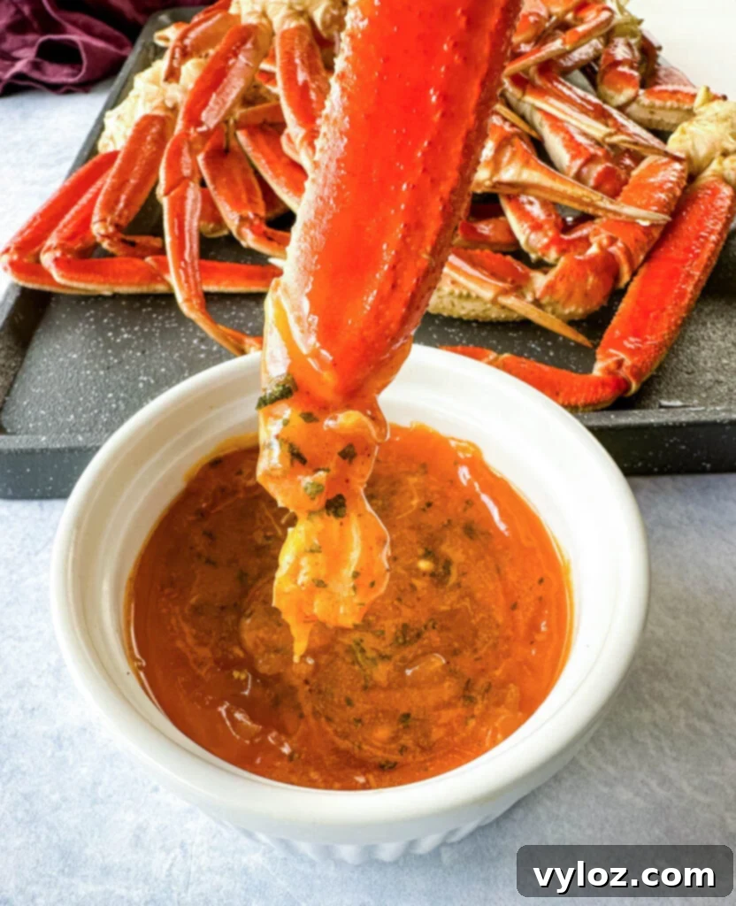 Smoked crab leg being dipped into a bowl of smoky garlic butter, creating a delicious mess