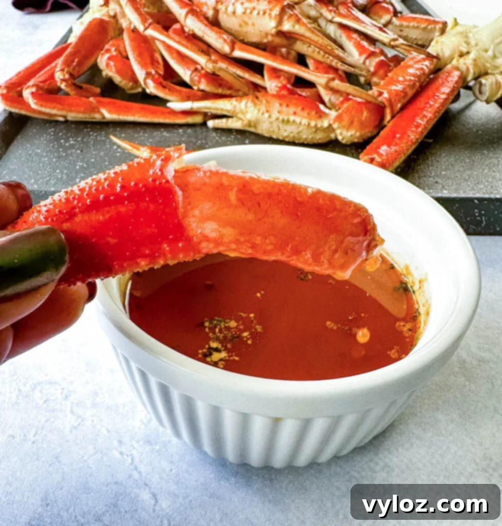 Close-up of a smoked crab leg, partially dipped in smoky garlic butter, showcasing the golden color
